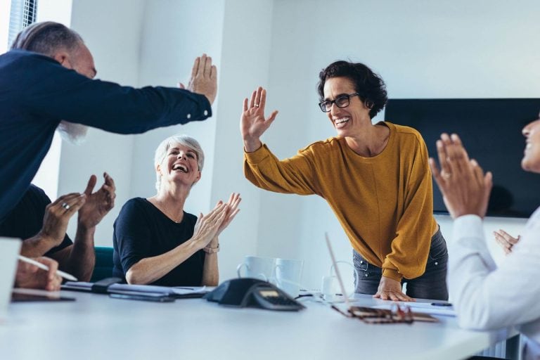 Business people clapping at a meeting, showcasing brand culture.