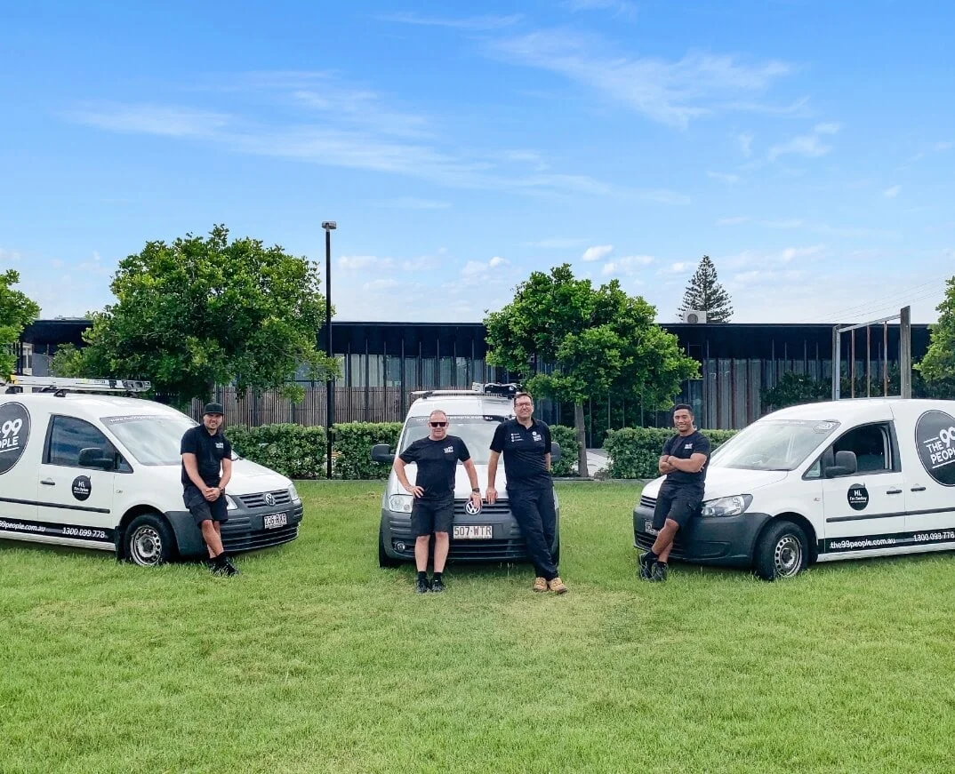 A group of men standing next to vans in a grassy area.