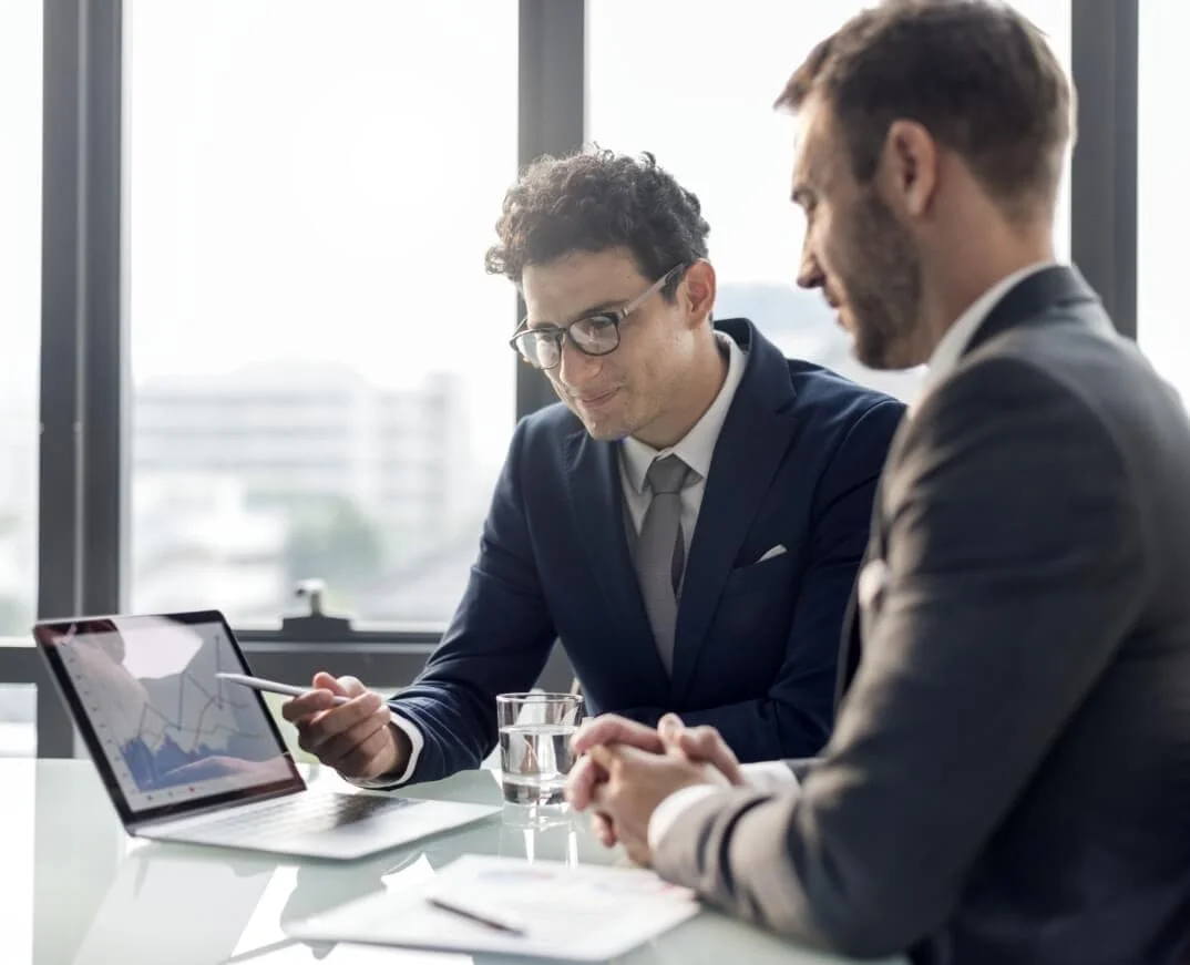 Two businessmen looking at a graph on a laptop.