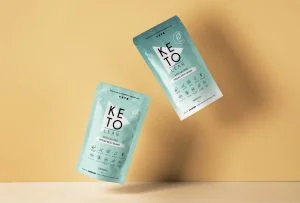 Two packets of keto powder on a yellow background.