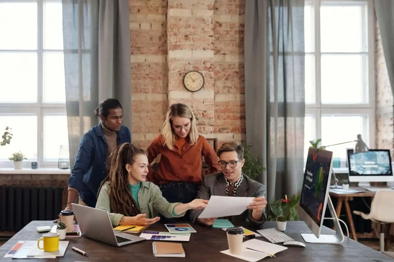 A group of people strategizing marketing tactics around a table in an office.