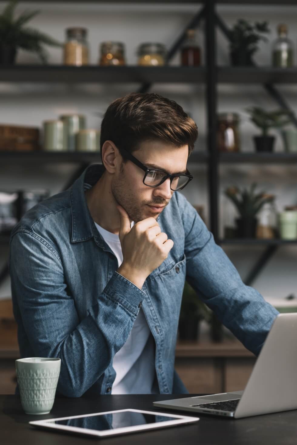 A man sitting at a desk with a laptop and a cup of coffee.