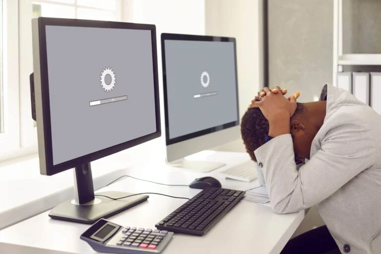 A man is performing website maintenance at a desk with two monitors.