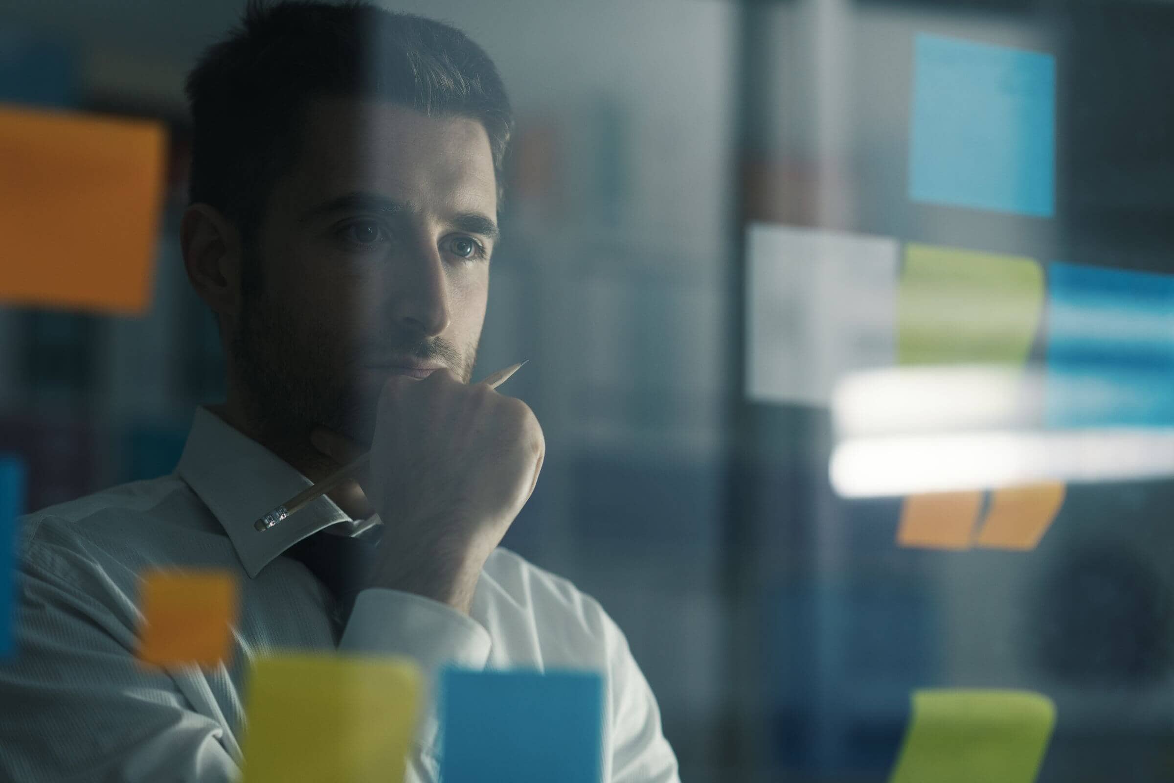 A businessman strategizing his digital marketing plan with sticky notes on a glass wall.